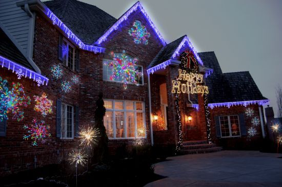Professionally installed Christmas lights on the outside of a home with a snowflake, Happy Holidays Sign, and spritzers.