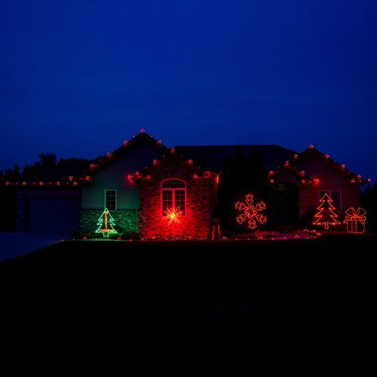 House with red christmas lights installed with yard decorations.