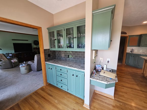 Cabinet doors painted a bright sage green with knobs towards the middle of the cabinet edge.
