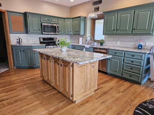 Kitchen with cabinets painted a sage green color and the island left golden oak.