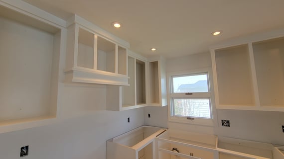 Close up of white painted kitchen cabinets with the doors removed.