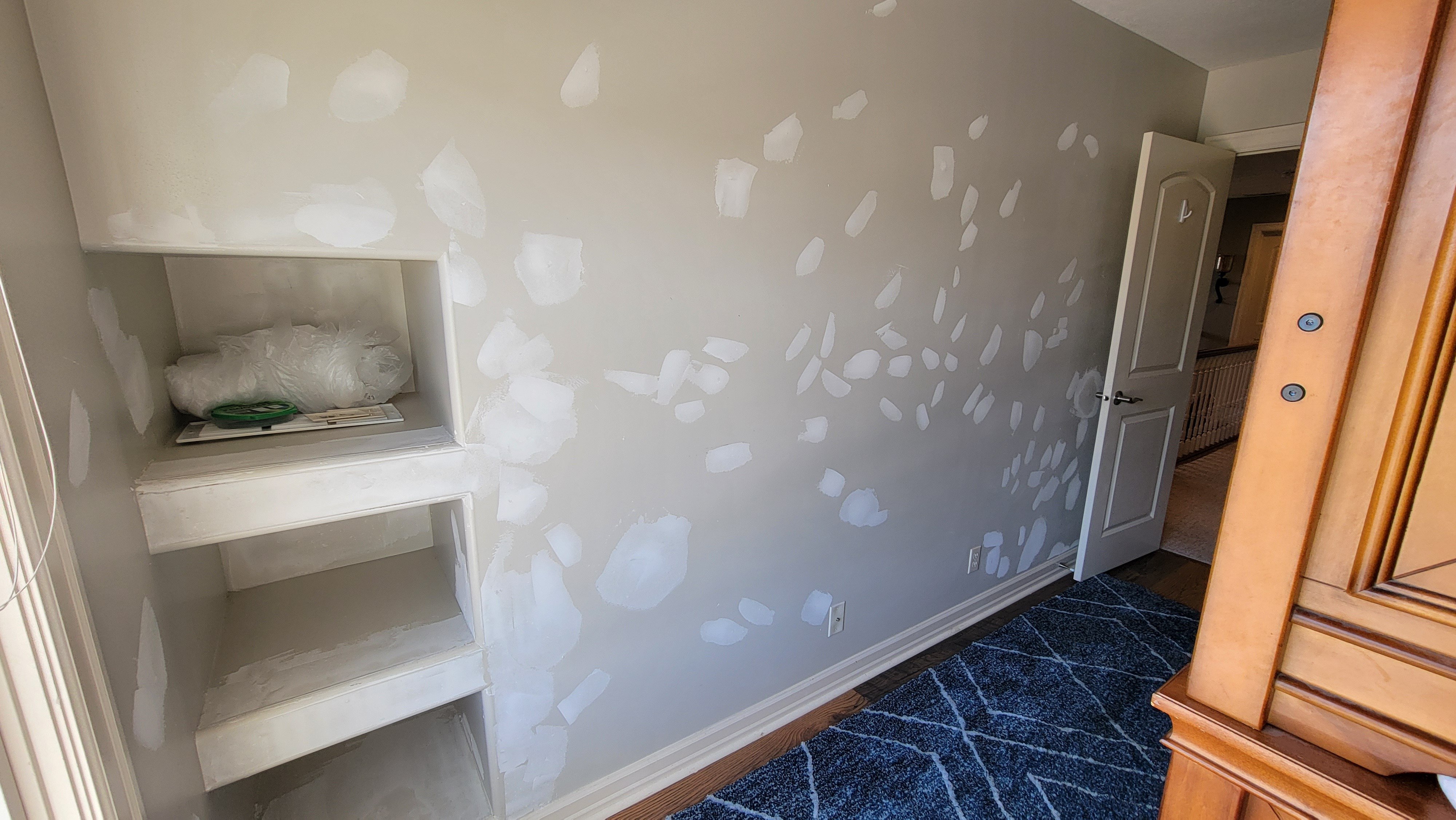 Wall with a lot of drywall touch ups that are repaired and spot primed.