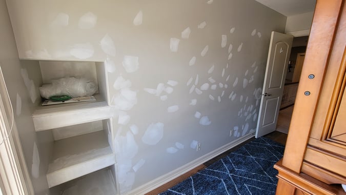 Drywall patched and primed before painting a wall.