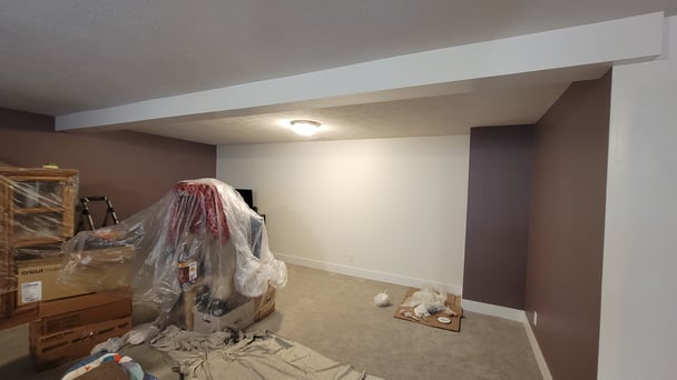 Basement freshly painted with a white accent walls and other brown walls.