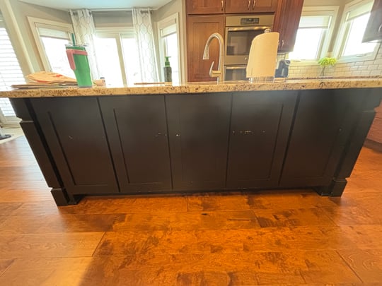 Scratched and chipping paint on a kitchen island in a dark color before painting a beige greige color in an Omaha home.