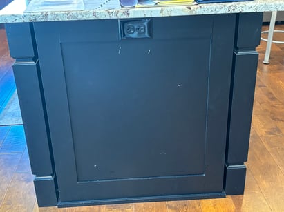 Kitchen island in a dark black color with chipping paint.