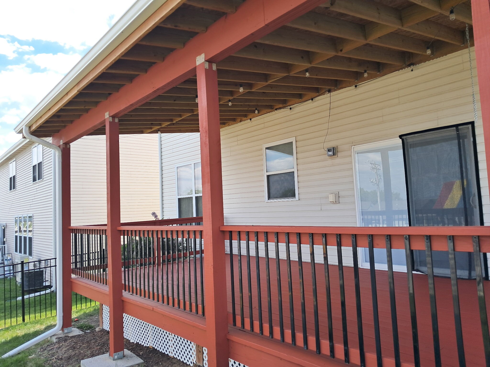 Backside of deck stained a red stain with metal rods on the back of a home in Omaha, NE.