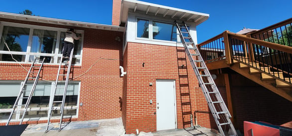 Repairs and painting being done on a home in Omaha NE with white trim and accents on a brick house.