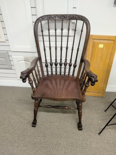 Antique chair with lion on arm rests stained a warm deep brown tone.