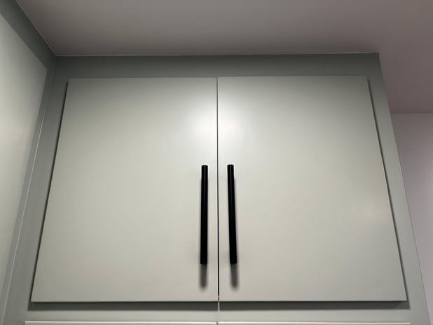 Sage green painted cabinet doors with long black handles.