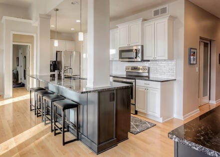 Kitchen with off-white walls, white cabients, stainless steel appliances, and a dark brown island.