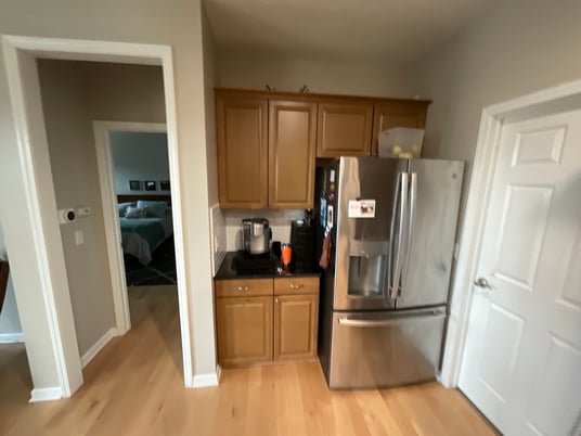 Kitchen cabinets in natural golden oak with white woodwork and a stainless steel fridge.
