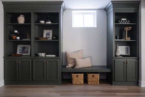 Bookshelf painted a dark sage green with gold knobs on the doors.