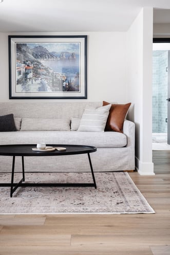 Living room space with white walls and trim and a grey couch.