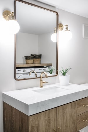 Bathroom with light grey walls, gold hardware and fixtures, and white countertop.