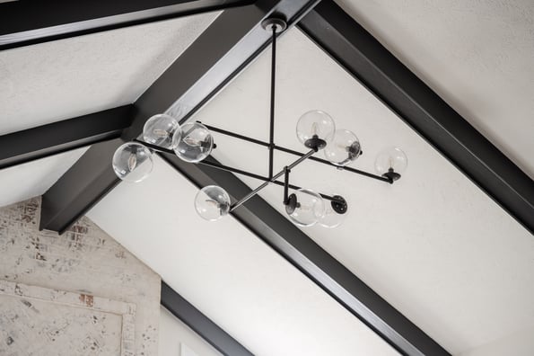 Ceiling painted white with black beams and a black light fixture with multiple clear bulbs.