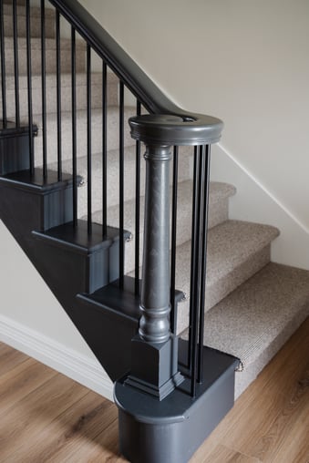 Staircase with railings painted black with white walls.