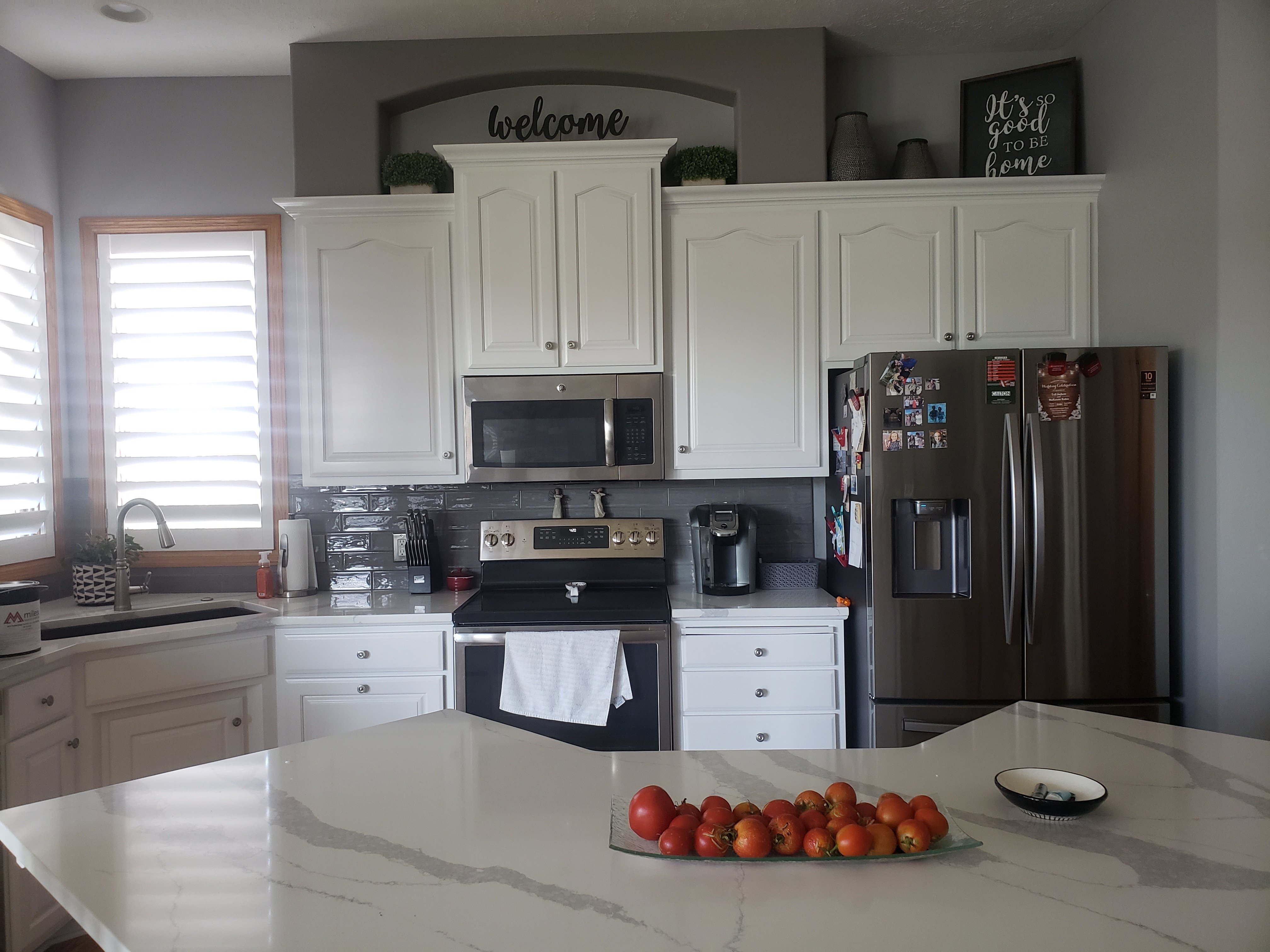 Kitchen with cabinets painted white and marble countertops.