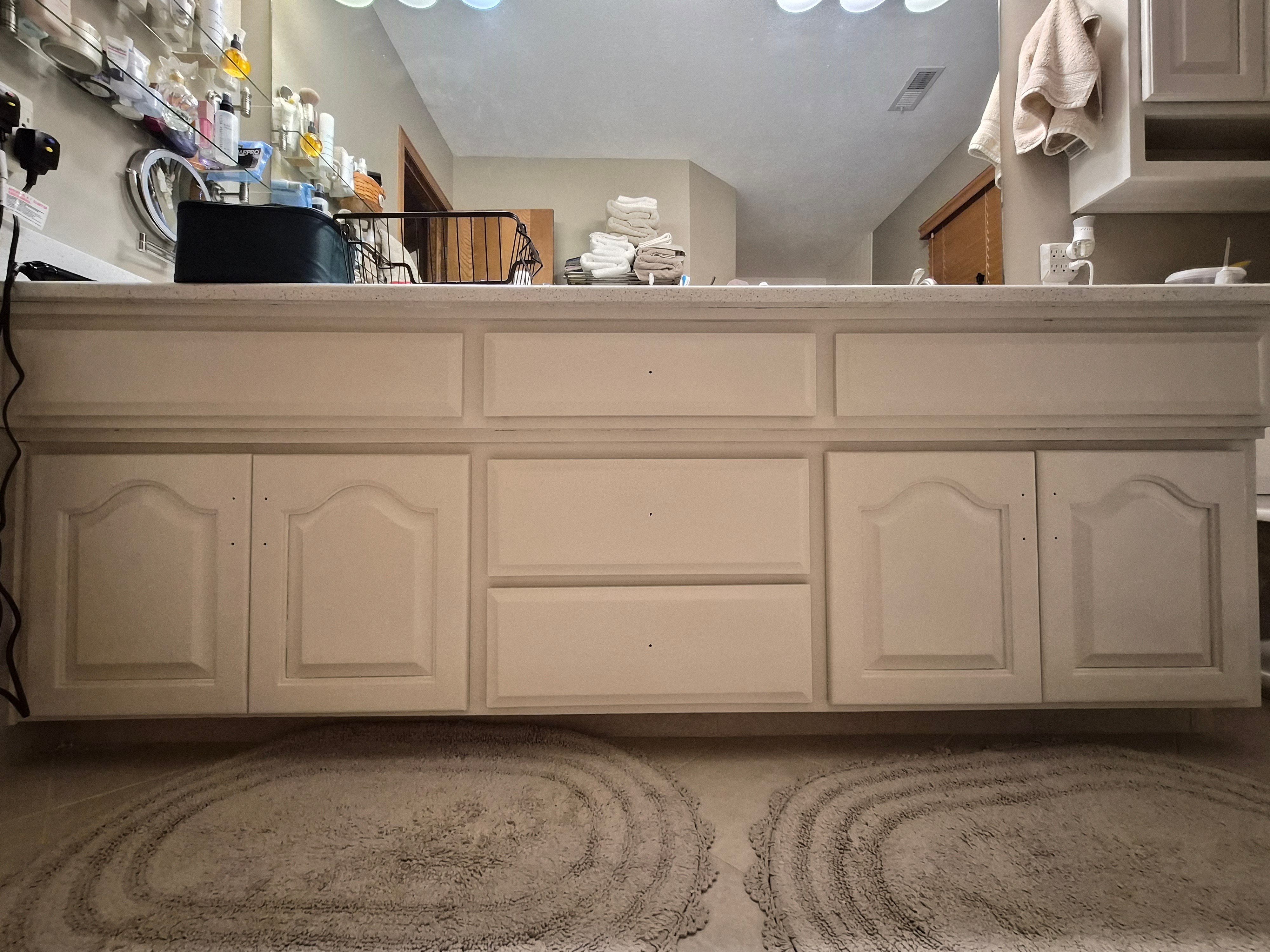 Bathroom cabinet vanity and counter with white painted cabinet doors and drawers with no handles installed.
