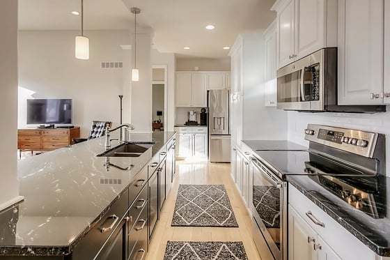 Kitchen with white cabinets along the wall and a dark painted island in the center.