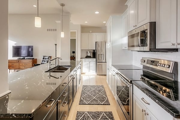 Hallway view of kitchen with white painted cabinets in SW 7626 Zurich White and a darker island in SW greenblack.