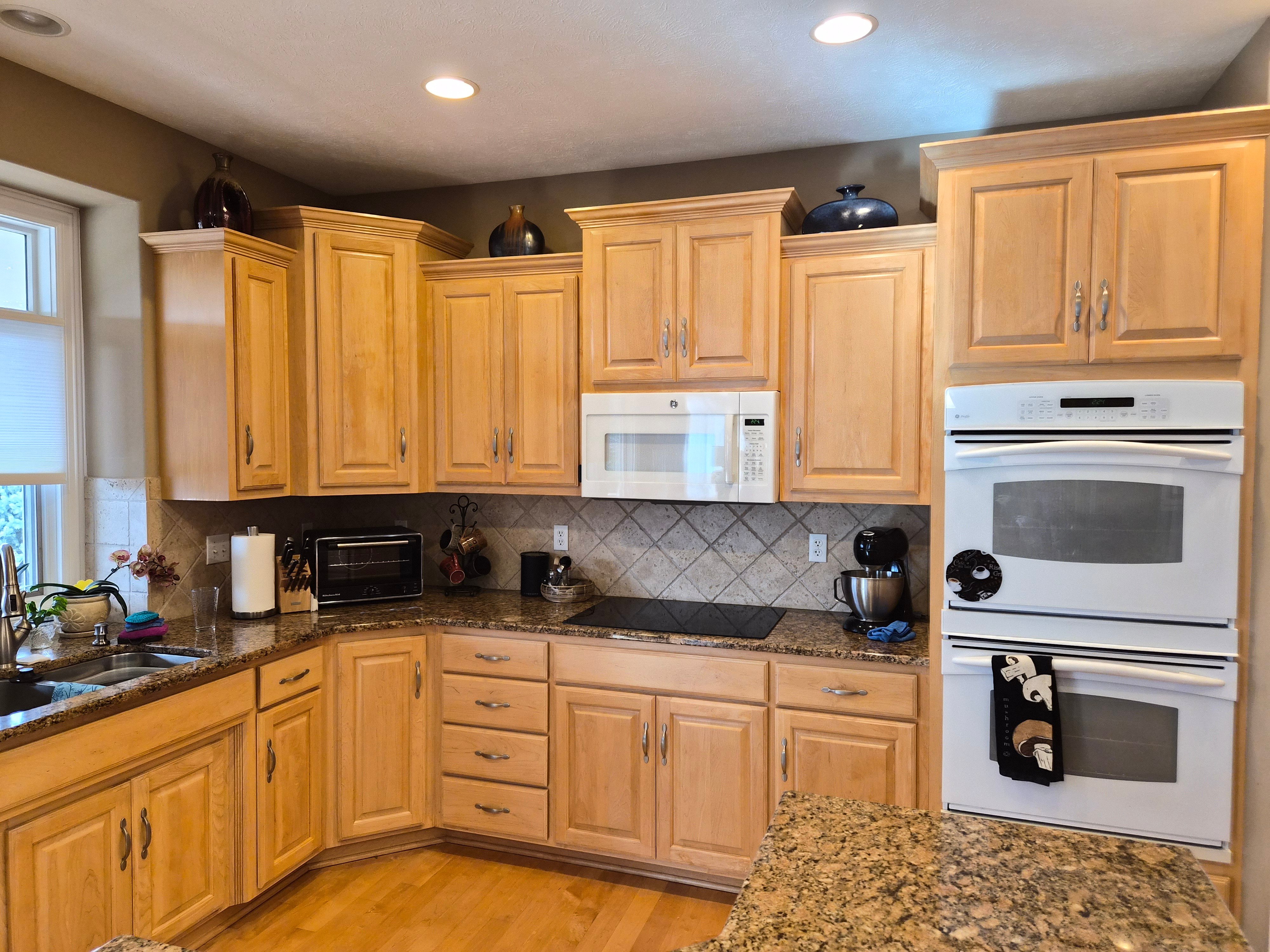 Kitchen cabinets that are naturally a light warm wood that have been painted and refinished with a clear coat by Brush & Roll Painting in Omaha, NE.