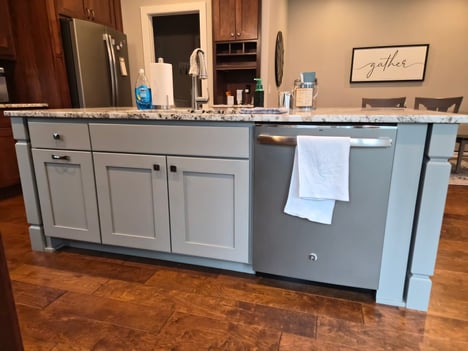 Kitchen island painted a beige color with knobs for on doors.