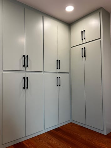 Large cabinet doors painted sage green with big black handles.