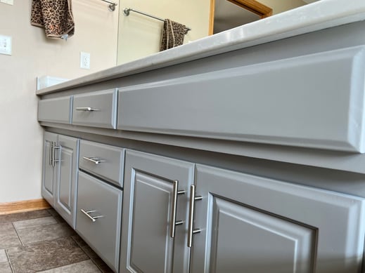 Bathroom vanity cabinets painted a soft light grey color with silver handles.