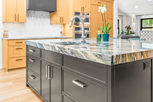 Brushed nickel handles on kitchen island cabinets that are painted a dark brown color.