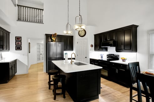 White kitchen walls and countertops and black cabinets.