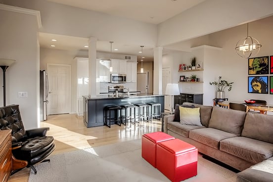 Interior living room and kitchen with off white walls and white cabinets with a dark painted island.