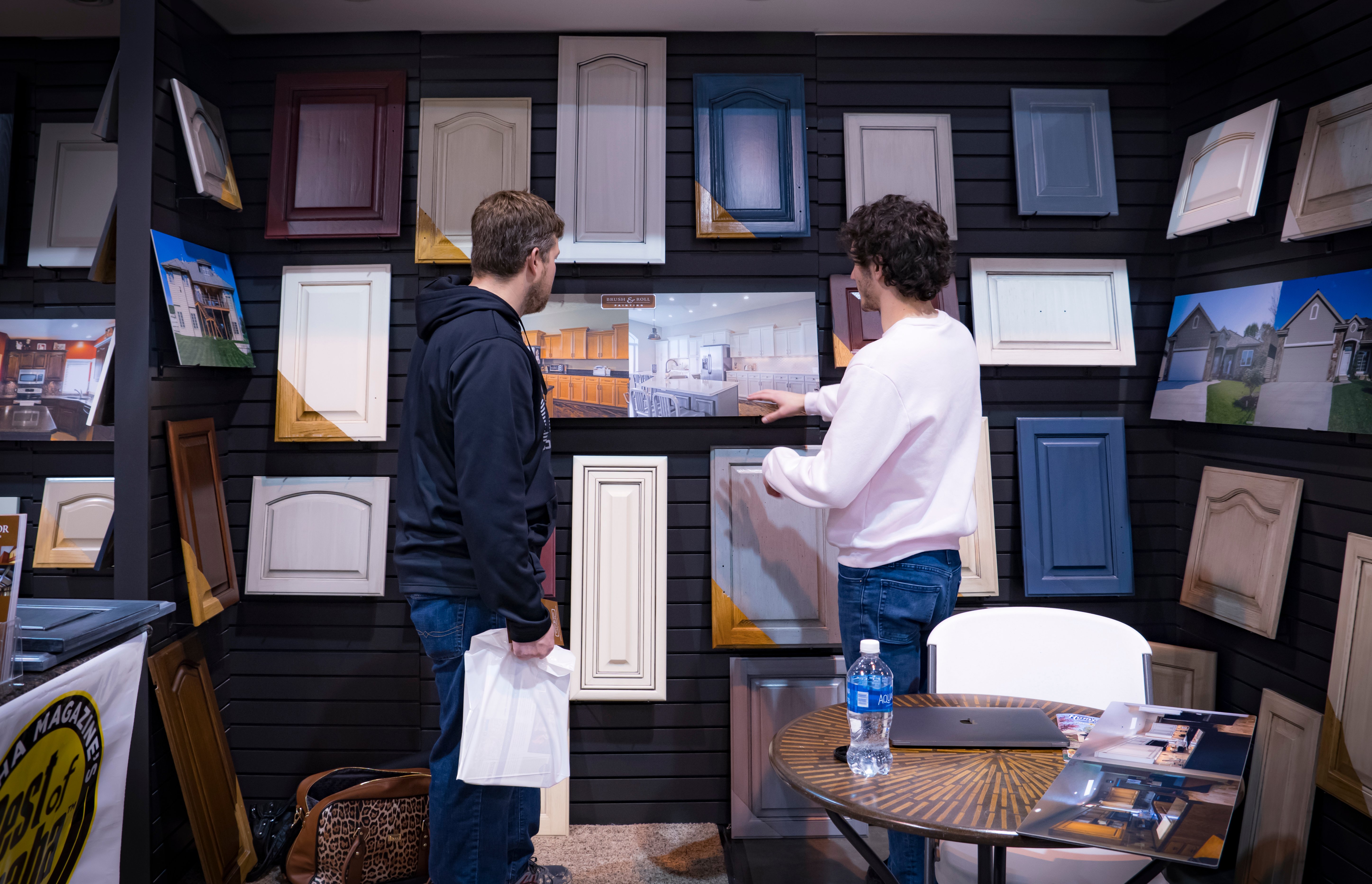 Brush & Roll Painting painter looking at kitchen cabinet painting photos with a homeowner at a home show at the CHI Health Center in Omaha, NE.
