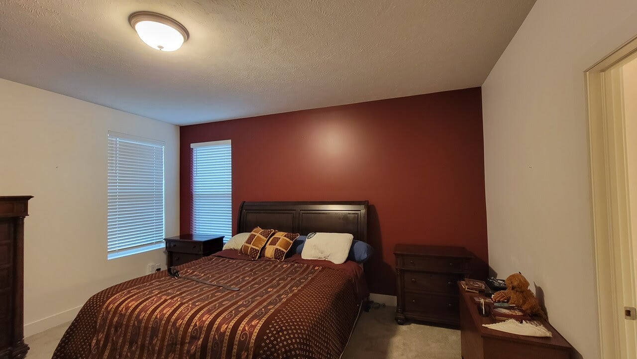 Bedroom with a dark maroon accent wall with the other walls painted white in a home in Omaha, NE.