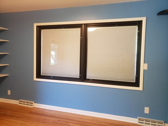 Bedroom with blue walls and white window trim and baseboards.