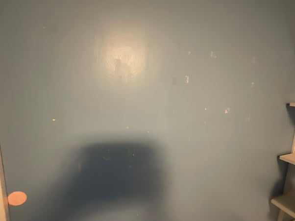 Before interior painting a wall blue with scuffs and marks on the drywall.