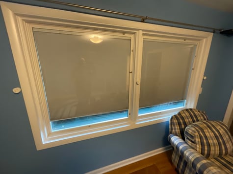 Window trim painted white with cool dark blue walls inside a bedroom in a home in Omaha.