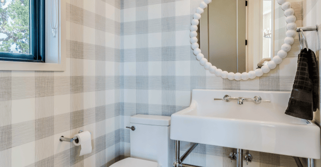 Bathroom with plaid grey wallpaper and white fixtures.