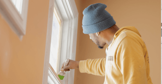 Painter brushing white paint onto a window trim in Omaha, NE.