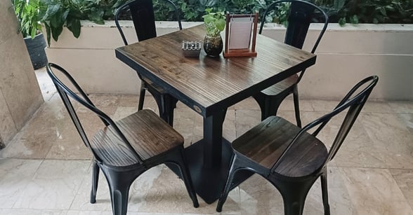 Metal patio table and chairs with a wood look and black legs.