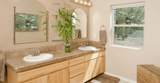 Bathroom with beige walls and oak cabinets and warm brown countertops.