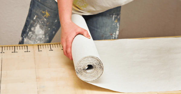 Painter rolling out a sheet of wallpaper in Omaha, NE.