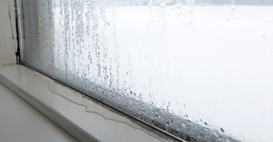 Window showing humidity and water dripping on window sill in a puddle.