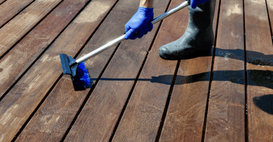 Person scrubbing a deck with a broom scrubber.