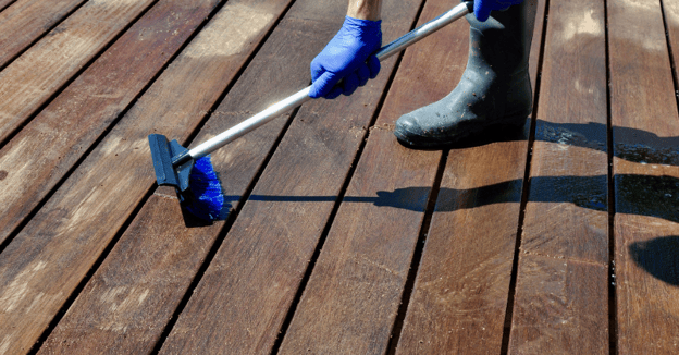 Person cleaning wood deck with a sponge mop.