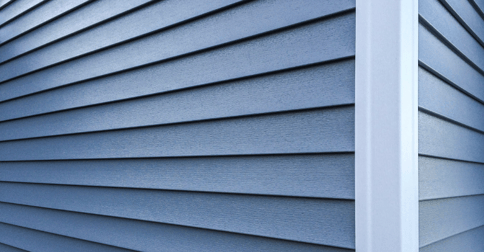 Close up of deep blue painted siding of home's exterior with blue trim on a corner.