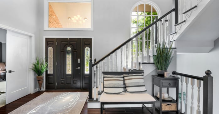 Entryway to a home with dark wood floors and grey flat paint with white trim and office door.