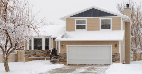 Exterior of home in Omaha with snow on it, the color of the home is a yellow / beige with white trim and stone on the lower half.