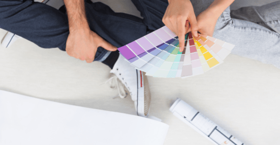 Couple sitting on the floor looking at color gradient swatches for their painting project.