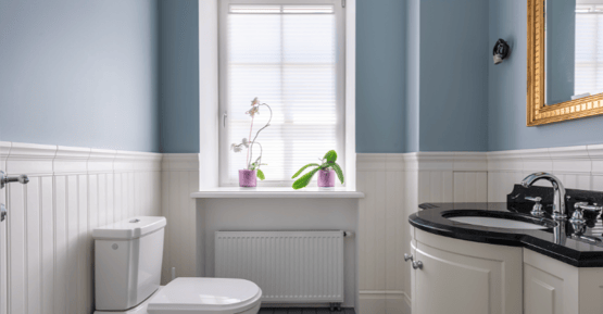 Small bathroom with soft light blue walls and shiplap on bottom half painted white.